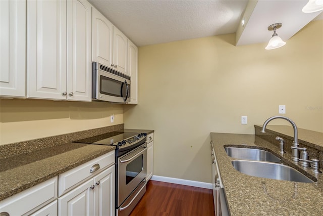 kitchen with appliances with stainless steel finishes, dark stone countertops, white cabinetry, and sink