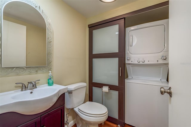 bathroom featuring stacked washer and clothes dryer, vanity, and toilet