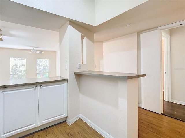 kitchen featuring light hardwood / wood-style floors, kitchen peninsula, ceiling fan, and white cabinets