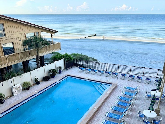 view of pool featuring a patio, a water view, and a view of the beach