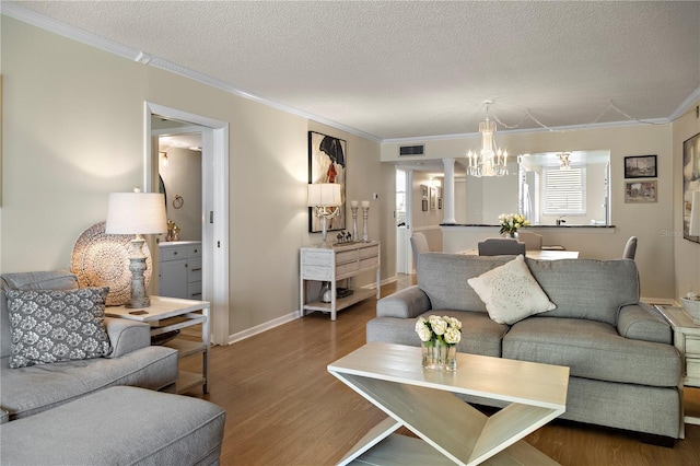 living room featuring an inviting chandelier, crown molding, a textured ceiling, and hardwood / wood-style flooring