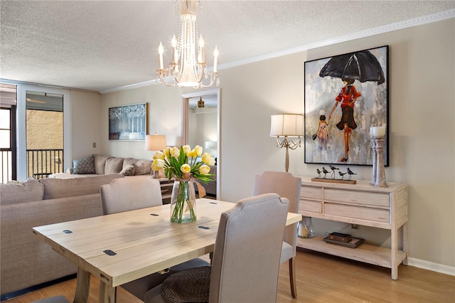 dining space with light wood-type flooring, crown molding, a textured ceiling, and a chandelier