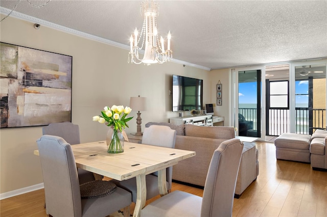 dining space with light hardwood / wood-style floors, a textured ceiling, a notable chandelier, floor to ceiling windows, and ornamental molding