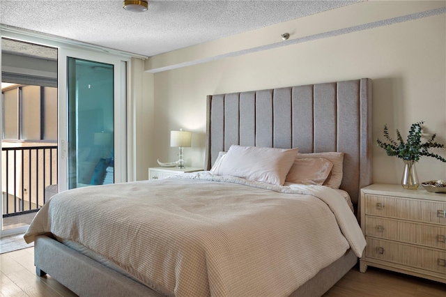 bedroom with light hardwood / wood-style flooring, a textured ceiling, and access to exterior