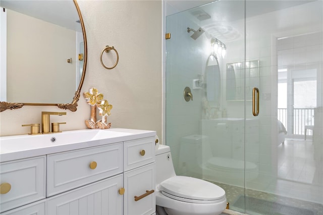 bathroom featuring a shower with door, vanity, and toilet