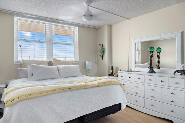 bedroom with wood-type flooring, a textured ceiling, and ceiling fan