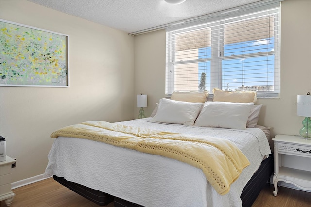 bedroom with a textured ceiling and dark hardwood / wood-style floors