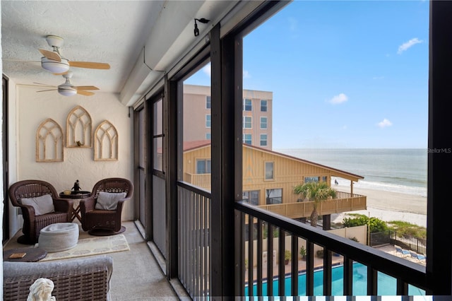 balcony with a water view, a beach view, and ceiling fan