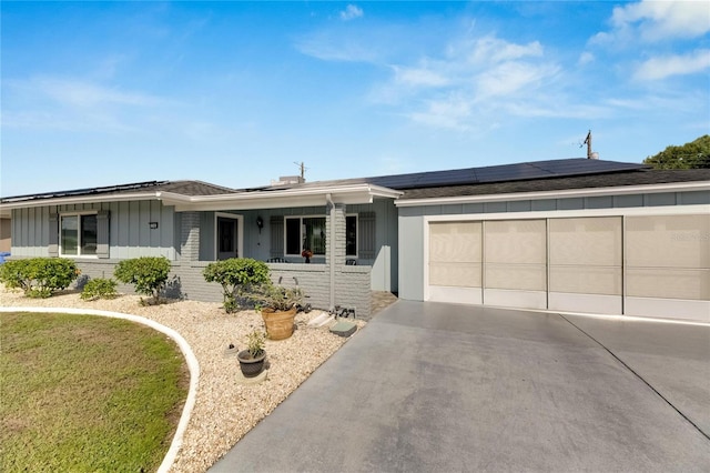 single story home with a garage, solar panels, and covered porch