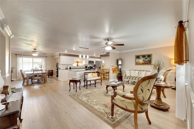 living room with light hardwood / wood-style flooring, ceiling fan, a textured ceiling, and ornamental molding