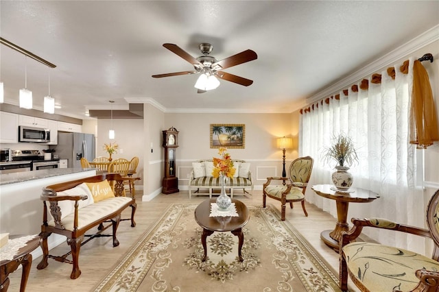 living area with ornamental molding, light wood-type flooring, and ceiling fan