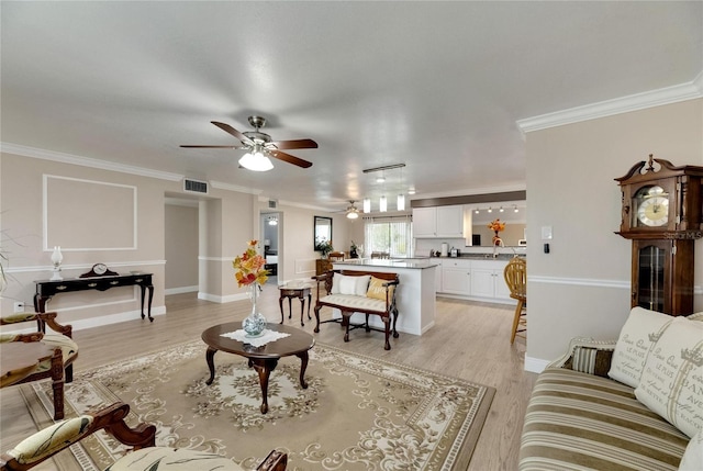 living room with ceiling fan, sink, light wood-type flooring, and ornamental molding