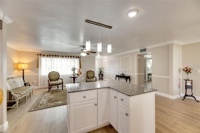 kitchen with white cabinets, ornamental molding, hanging light fixtures, and light hardwood / wood-style floors