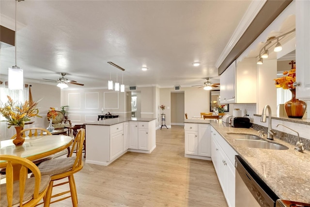 kitchen with white cabinets, kitchen peninsula, stainless steel dishwasher, decorative light fixtures, and light hardwood / wood-style flooring