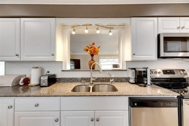 kitchen with appliances with stainless steel finishes, light stone countertops, sink, and white cabinets