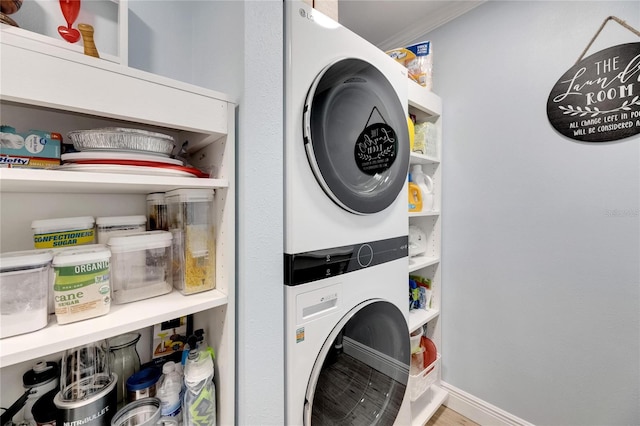 clothes washing area with stacked washing maching and dryer and ornamental molding