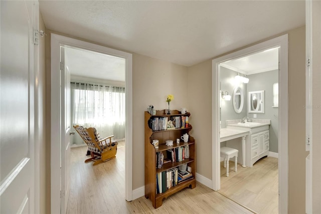 corridor featuring a textured ceiling, light hardwood / wood-style flooring, and sink