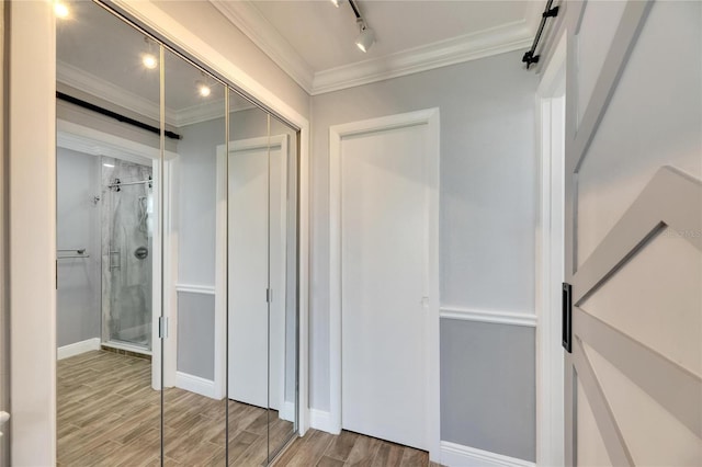 bathroom with hardwood / wood-style flooring, a shower with shower door, and ornamental molding