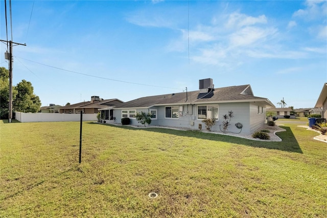 back of property featuring central AC unit and a yard