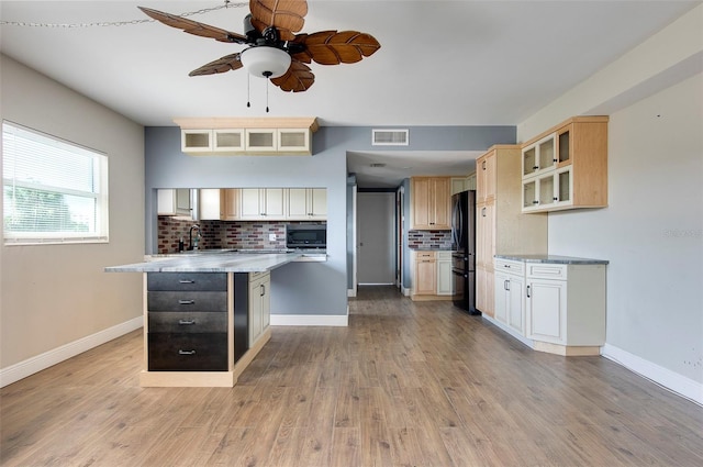 kitchen with light wood-type flooring, backsplash, ceiling fan, and black refrigerator