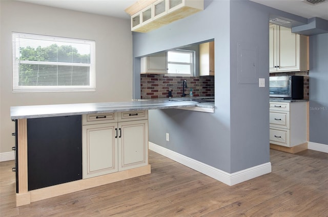 kitchen featuring decorative backsplash, light hardwood / wood-style floors, and cream cabinets