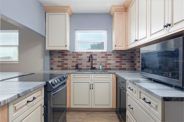 kitchen with sink, range with electric cooktop, decorative backsplash, light hardwood / wood-style flooring, and cream cabinets