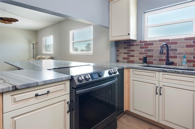 kitchen featuring a wealth of natural light, kitchen peninsula, and electric range