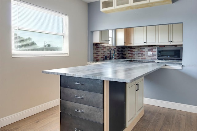 kitchen with backsplash, light hardwood / wood-style floors, a kitchen island, and cream cabinetry