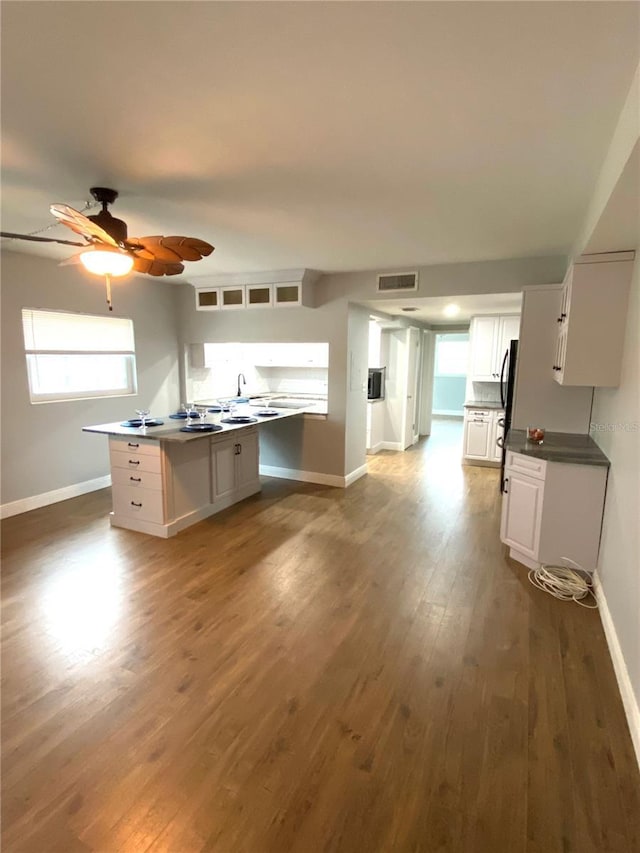 6000 2nd St E Unit 6, St Pete Beach, FL 33706 - kitchen with white cabinets, baseboards, freestanding refrigerator, wood finished floors, and a ceiling fan