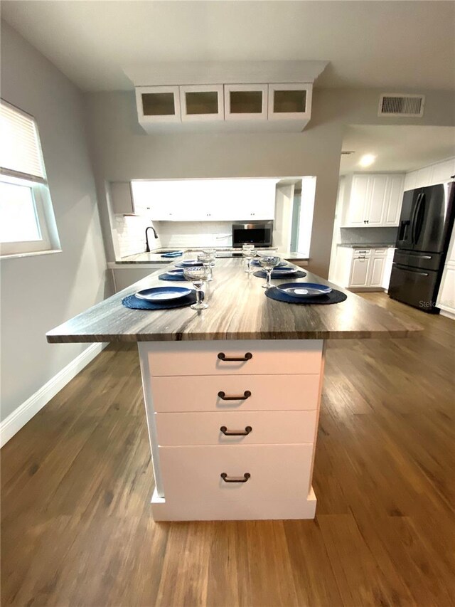 6000 2nd St E Unit 6, St Pete Beach, FL 33706 - kitchen featuring black fridge, white cabinetry, glass insert cabinets, dark wood-type flooring, and baseboards