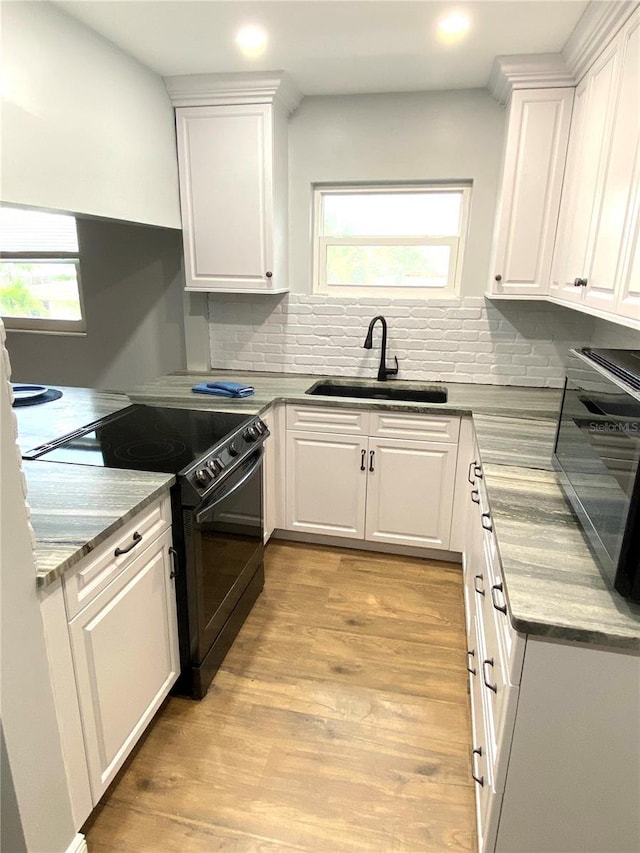 6000 2nd St E Unit 6, St Pete Beach, FL 33706 - kitchen featuring black electric range, a sink, white cabinetry, decorative backsplash, and recessed lighting