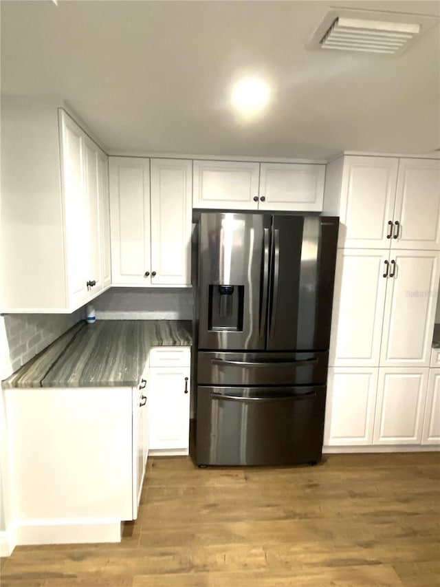 6000 2nd St E Unit 6, St Pete Beach, FL 33706 - kitchen featuring stainless steel fridge with ice dispenser, white cabinetry, light wood-style floors, dark countertops, and tasteful backsplash