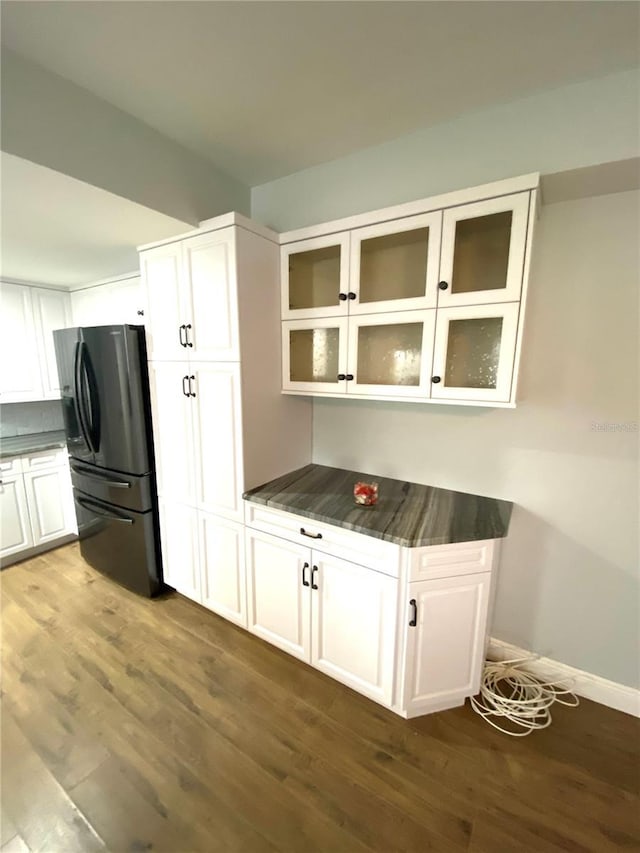 6000 2nd St E Unit 6, St Pete Beach, FL 33706 - kitchen featuring freestanding refrigerator, dark wood-style flooring, white cabinetry, dark countertops, and glass insert cabinets