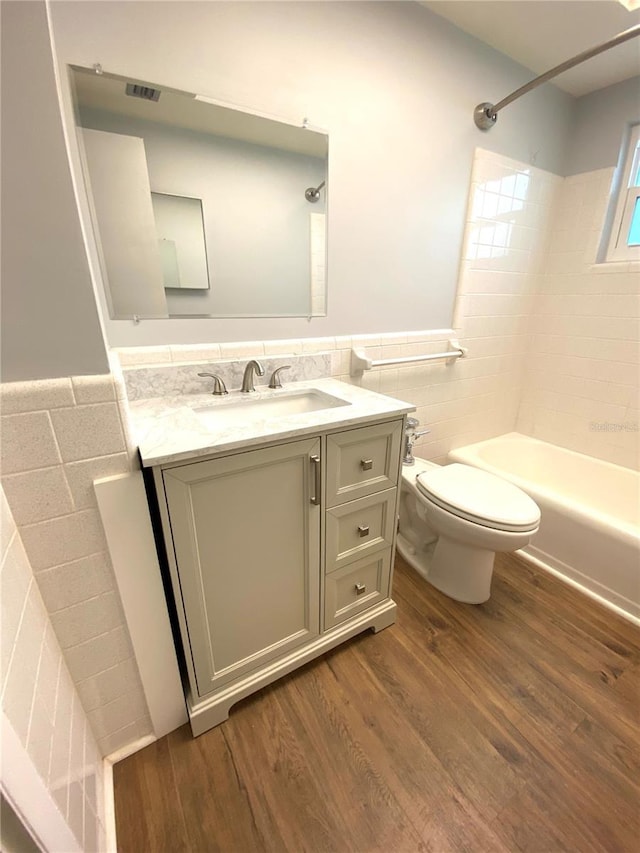 6000 2nd St E Unit 6, St Pete Beach, FL 33706 - full bathroom with tile walls, vanity, wood finished floors, toilet, and bathtub / shower combination