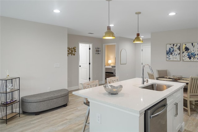 kitchen featuring light hardwood / wood-style floors, a kitchen island with sink, decorative light fixtures, sink, and white cabinetry