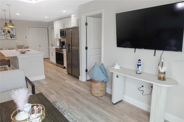 kitchen featuring light hardwood / wood-style floors, decorative light fixtures, sink, stainless steel appliances, and white cabinets