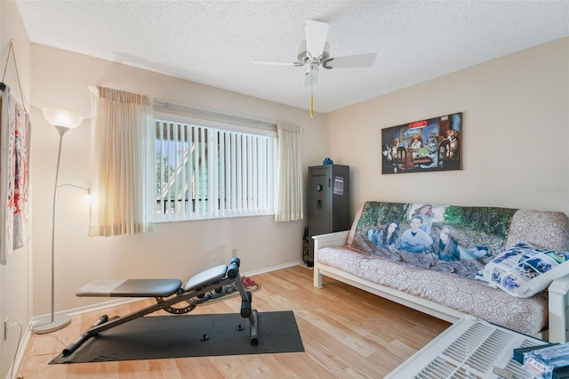 workout area featuring ceiling fan, a textured ceiling, and hardwood / wood-style floors