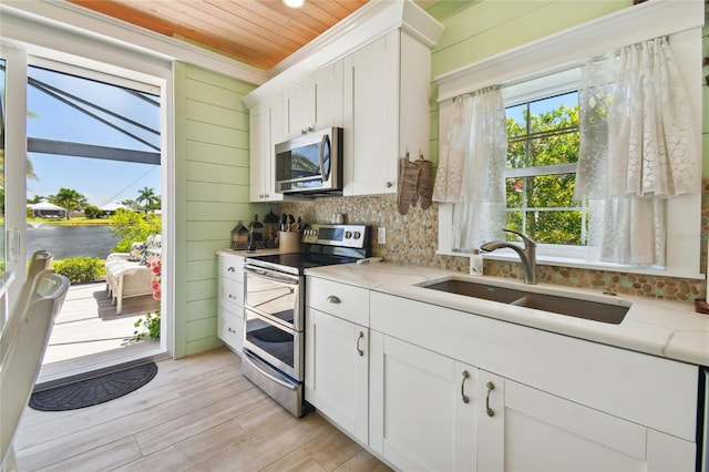 kitchen featuring light wood-type flooring, wood ceiling, white cabinetry, and stainless steel appliances