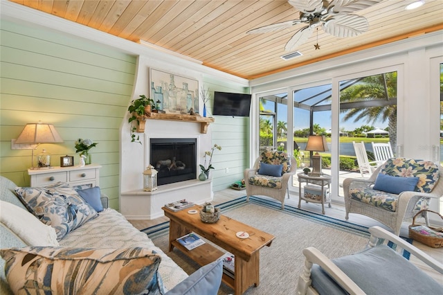 living room with wooden ceiling, crown molding, wooden walls, and ceiling fan