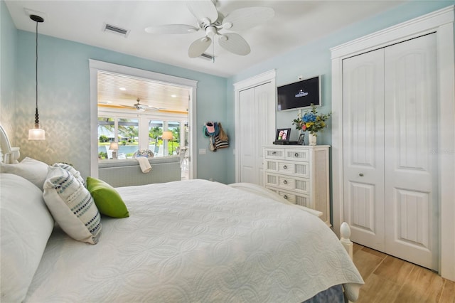 bedroom featuring light hardwood / wood-style flooring, multiple closets, and ceiling fan