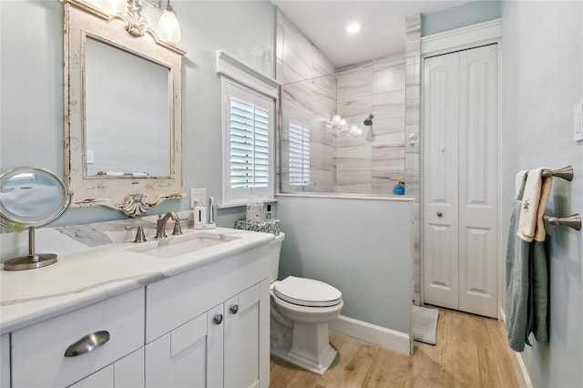 bathroom featuring vanity, toilet, hardwood / wood-style floors, and a tile shower