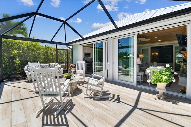 wooden terrace featuring ceiling fan, a patio, and a lanai