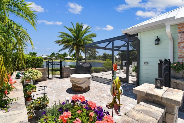 view of patio featuring a water view, glass enclosure, and a grill