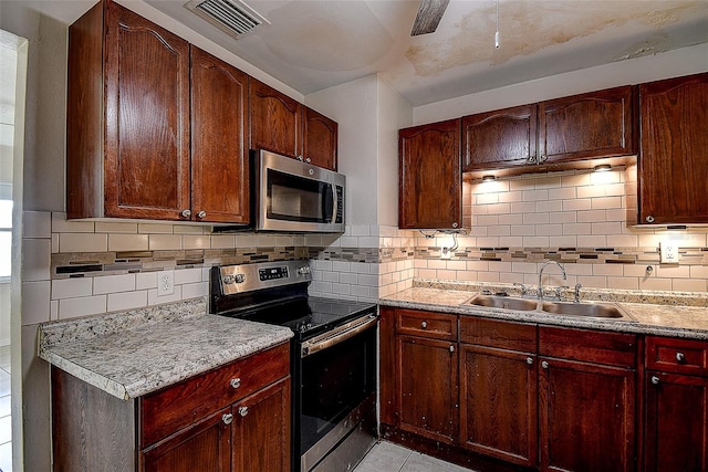 kitchen with light stone countertops, stainless steel appliances, backsplash, and sink