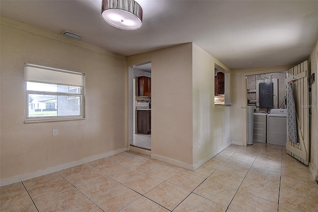 hall with washing machine and clothes dryer, electric panel, and light tile patterned flooring