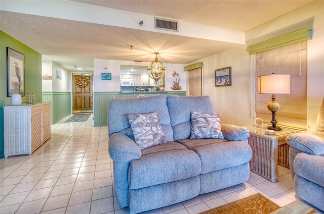 tiled living room with a notable chandelier and a textured ceiling