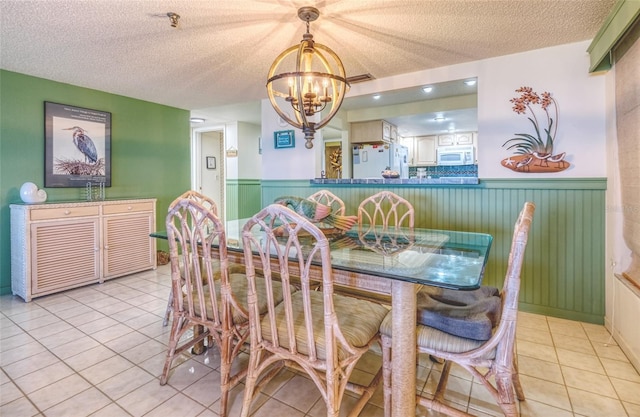 dining room with sink, a textured ceiling, light tile patterned floors, and a chandelier