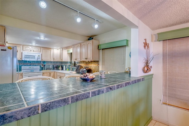 kitchen featuring white appliances, sink, a textured ceiling, decorative backsplash, and light tile patterned floors