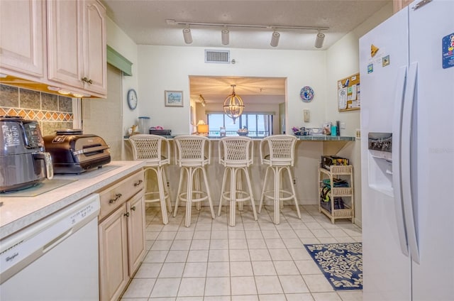 kitchen with track lighting, hanging light fixtures, backsplash, an inviting chandelier, and white appliances