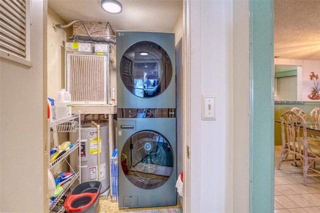 washroom featuring electric water heater, stacked washer and clothes dryer, tile patterned floors, and a textured ceiling